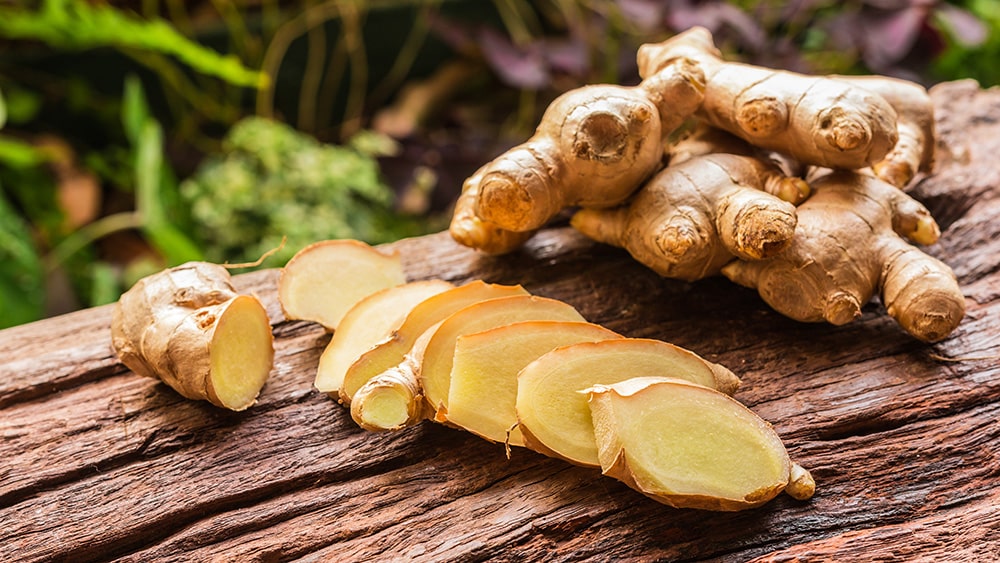 Ginger,Root,And,Sliced,On,Old,Plank,With,Nature,Background.