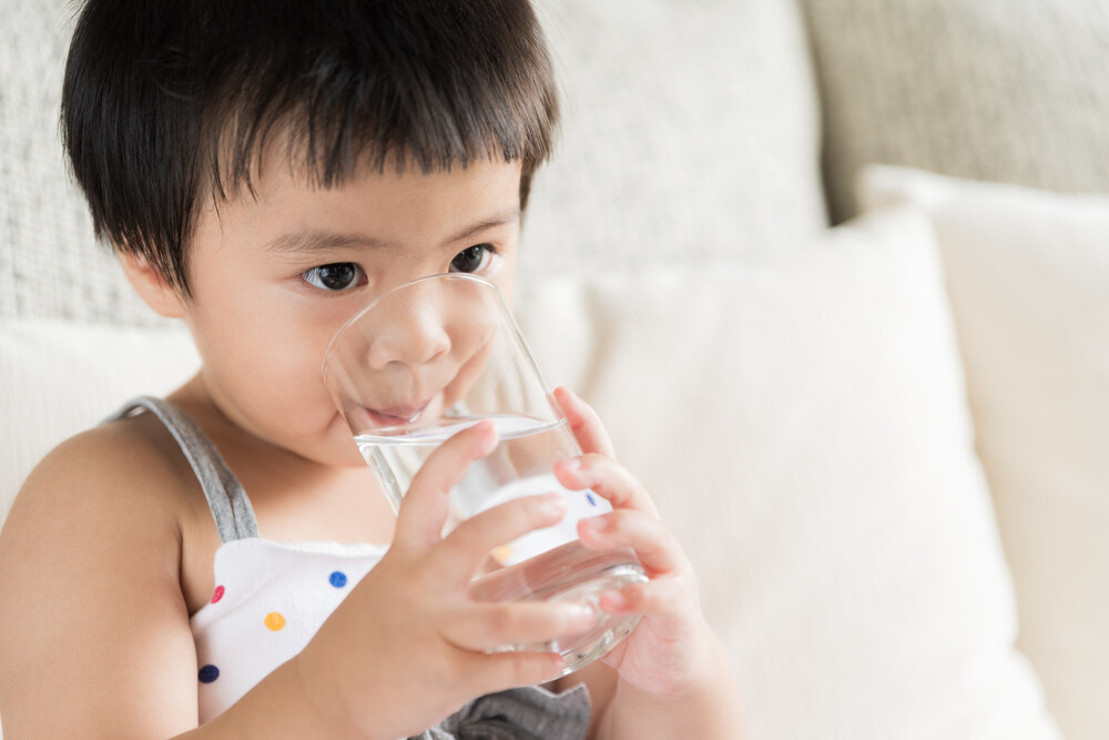 Bé bị tiêu chảy đang được mẹ cho uống dung dịch bù nước và điện giải.